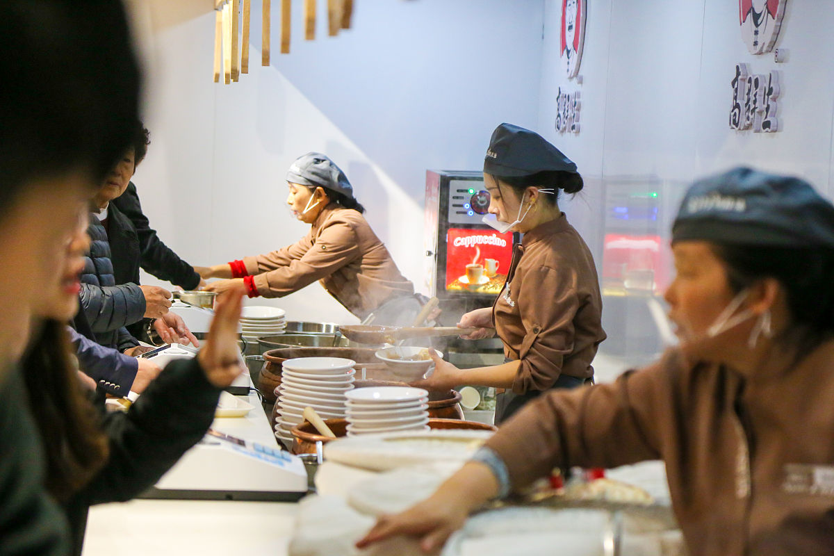 请描写一下一位老婆婆带着一个小孩一个年轻人走进了一家日系的面馆的画面