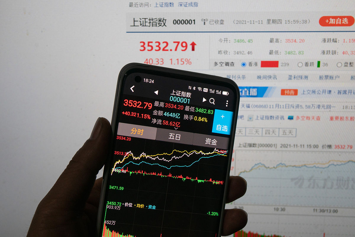2021年11月11日,上海,股民通过手机和电脑查看当天股市收盘股指.