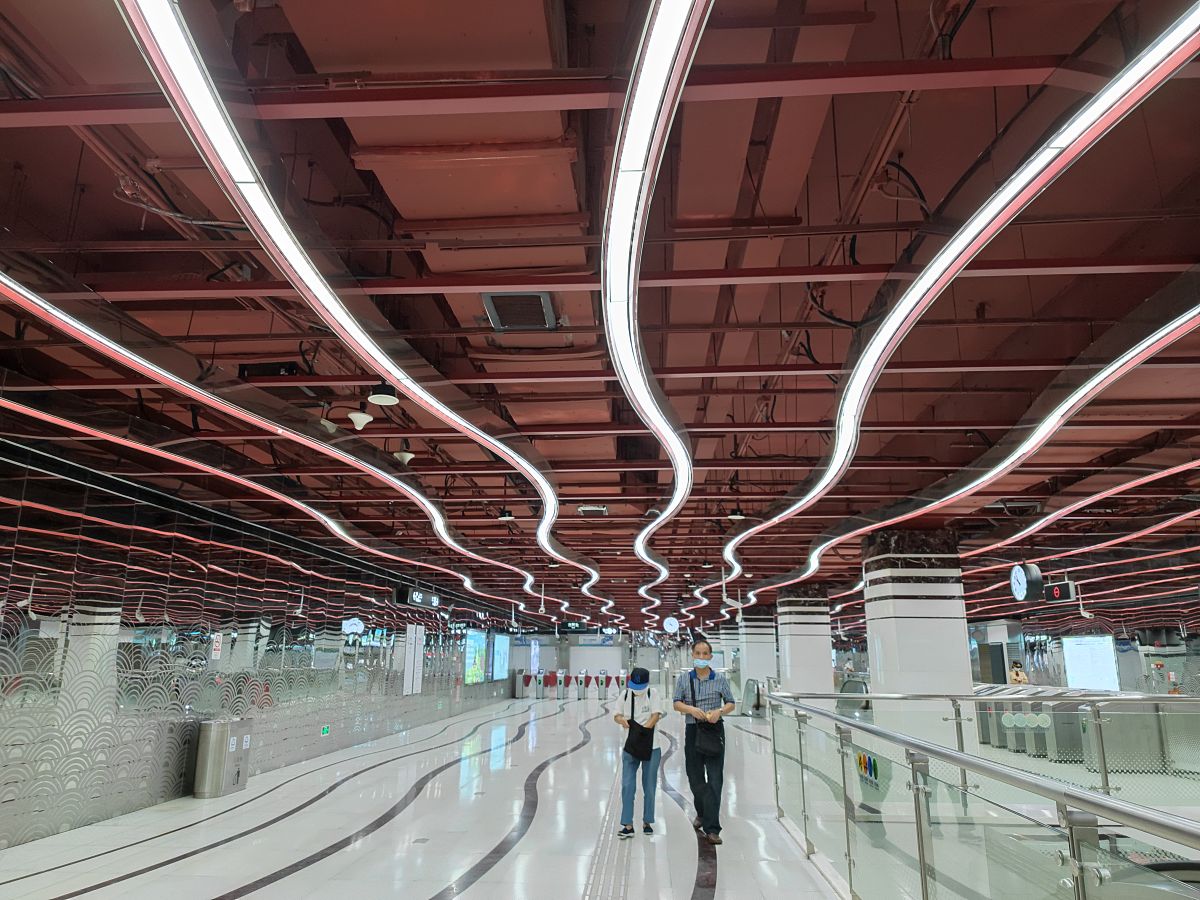 请改写以下段落让其更有逻辑重点突出：大多数火车站都建在地下导致封闭的、通风不良的环境客流量大促使与地面结构相比有明显的差异。首先地铁站完全依靠进出口的入口和通风井来获得新鲜空气使环境高度封闭。其次大量的乘客、照明和设备产生大量的热量和污染物。最后车站土壤覆盖层的热惯性使得热量难以在短时间内散去。地面建筑和地下建筑之间的这些明显差异使得通风和空调系统必须采取独特的方法。例如地铁站系统不仅要提供舒适的