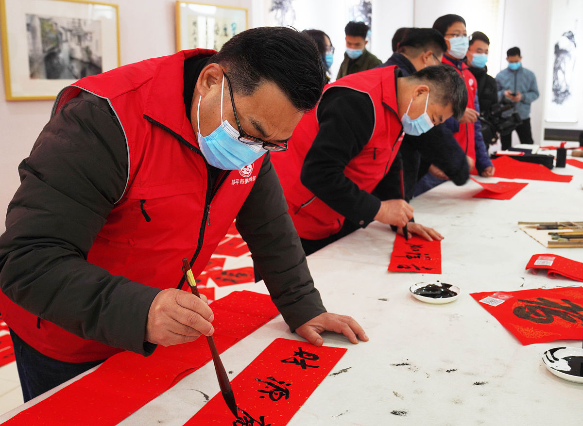 2021年2月3日,山东省邹平市书法志愿者在黄山街道社区书写福字和春联.