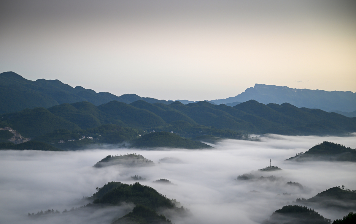 请用100字描述高处俯瞰村庄被云雾遮盖住了若隐若现雾气浓浓