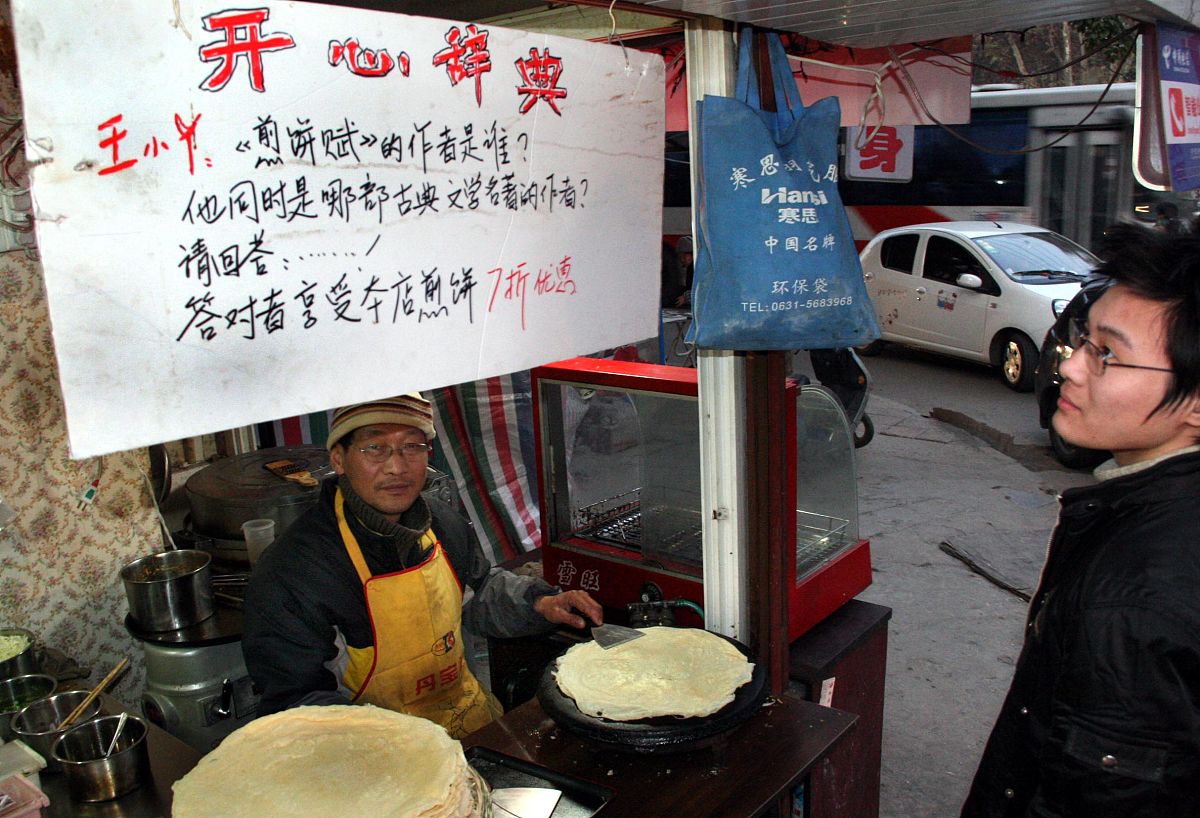 2009年12月6日,南京,有奖问答的牌子设在小店门脸上方,答对了煎饼七折