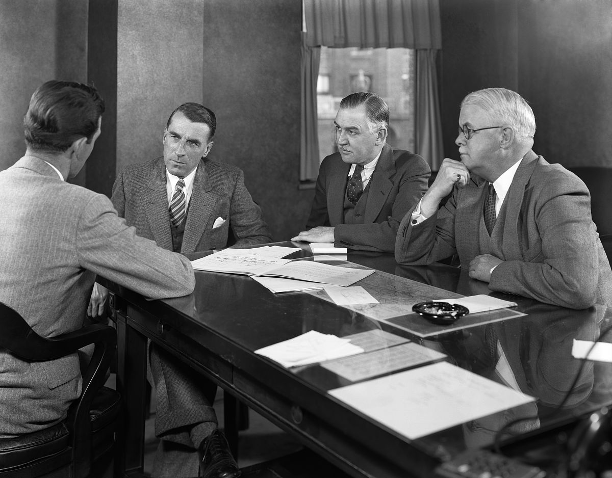 1930s 1940s four businessmen sitting at table in office conferen