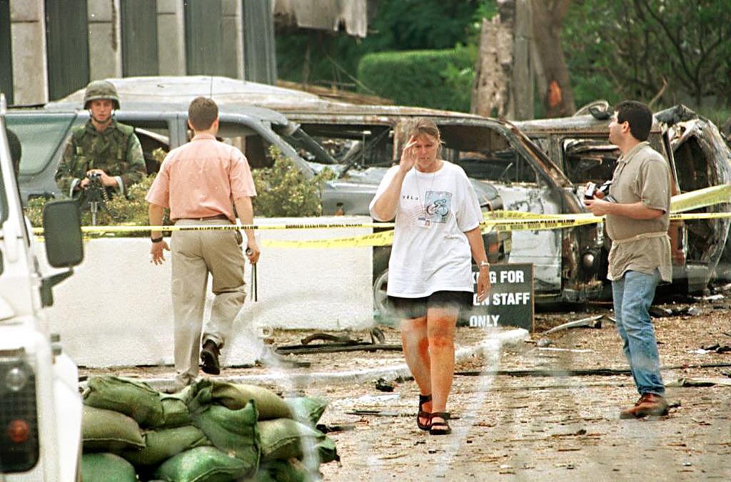 1998年8月9日,肯尼亚内罗毕,美国官员离开布满铁丝防护网的美国大使馆