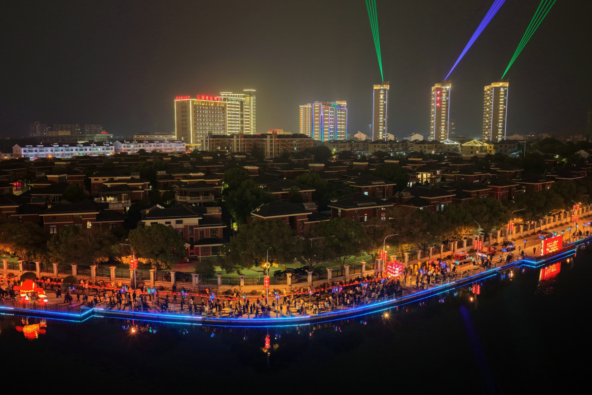 2026年3月3日,浙江东阳,迎灯队伍沿湖巡游,与乡村夜景