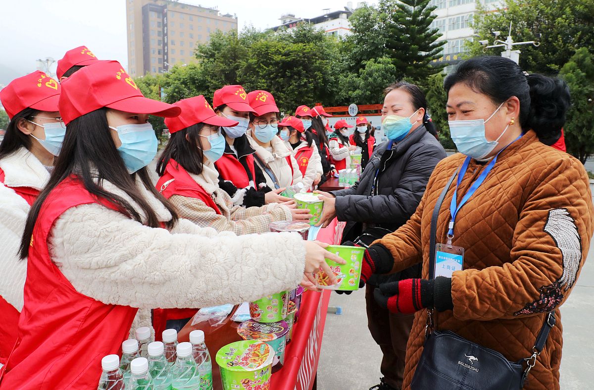 2022年1月19日,贵州黔东南,志愿者在榕江县汽车站门口给工作人员发送