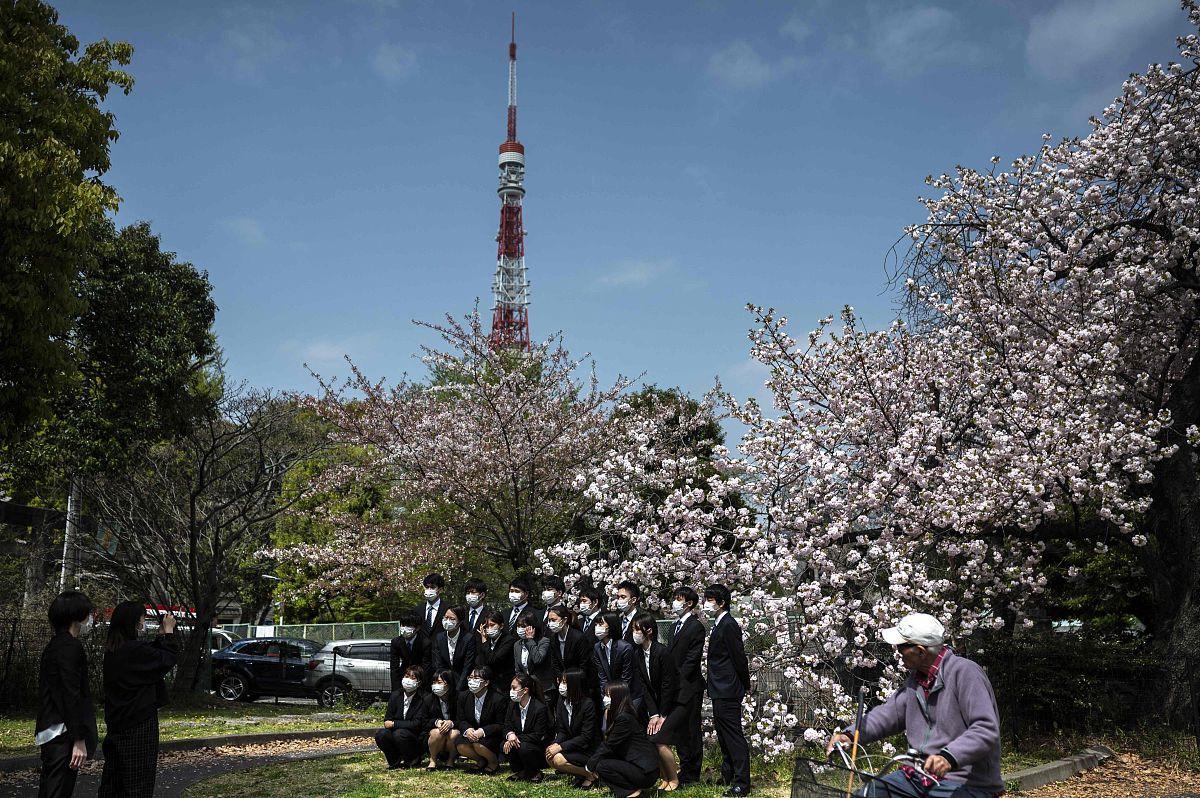 当地时间2021年4月1日,日本东京,新入职员工在樱花树下拍照.世界卫生