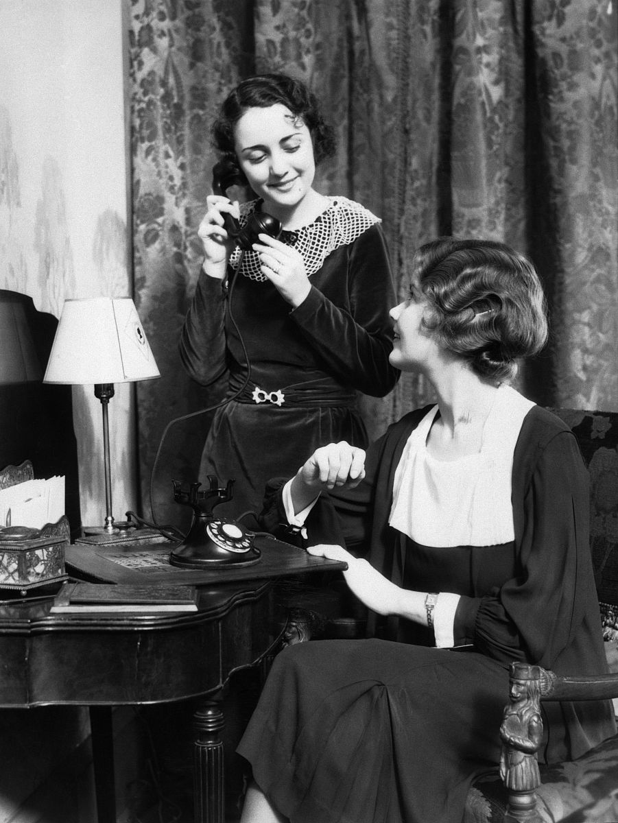 1930s two smiling well dressed women one sitting one standing by