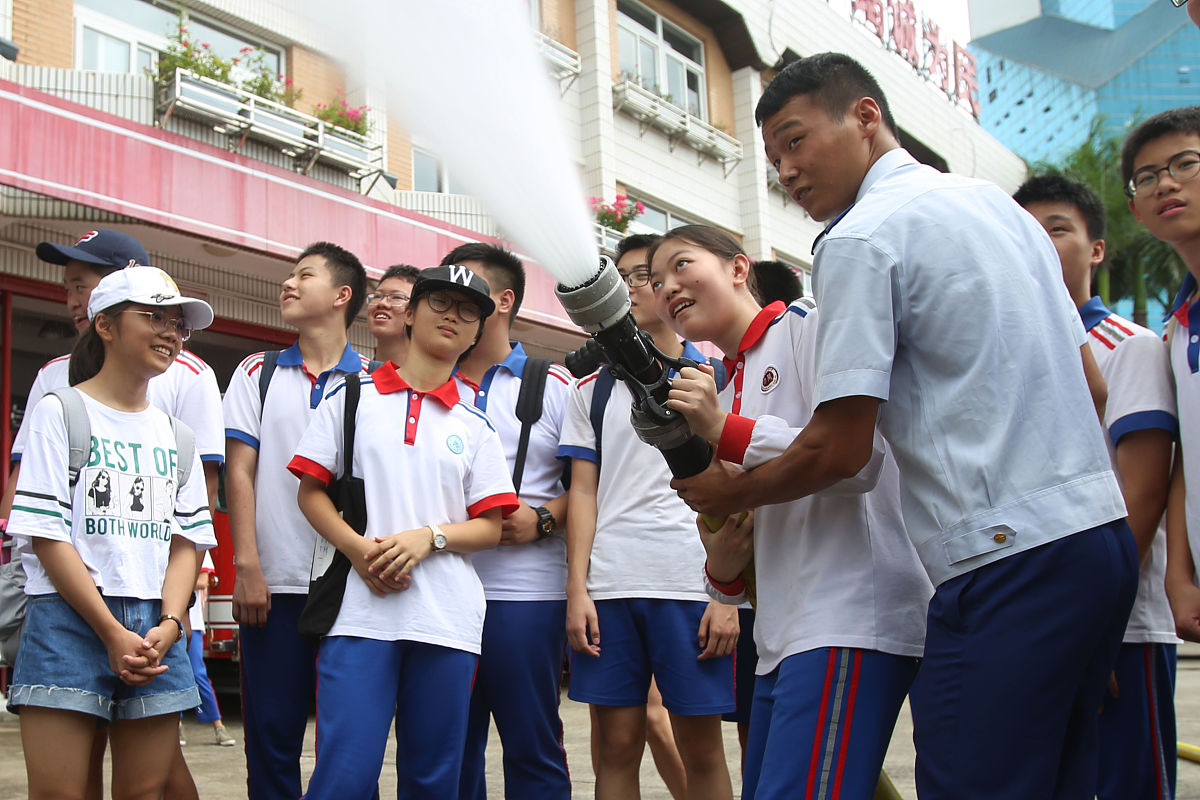 2019年7月9日,在厦门市消防支队特勤一中队营区内,中学生在消防员的指