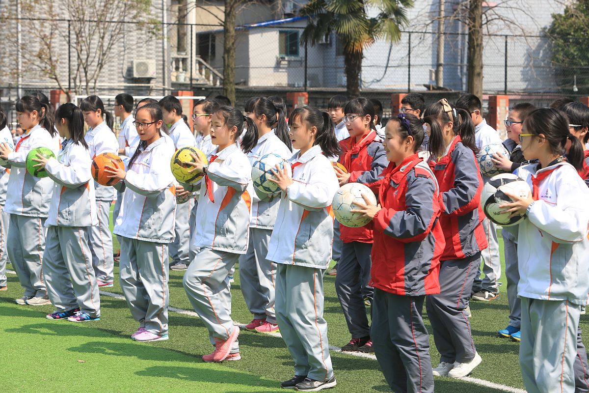2015年3月25日,杭州启航中学的学生抱着足球在体育课上跳操热身,动作
