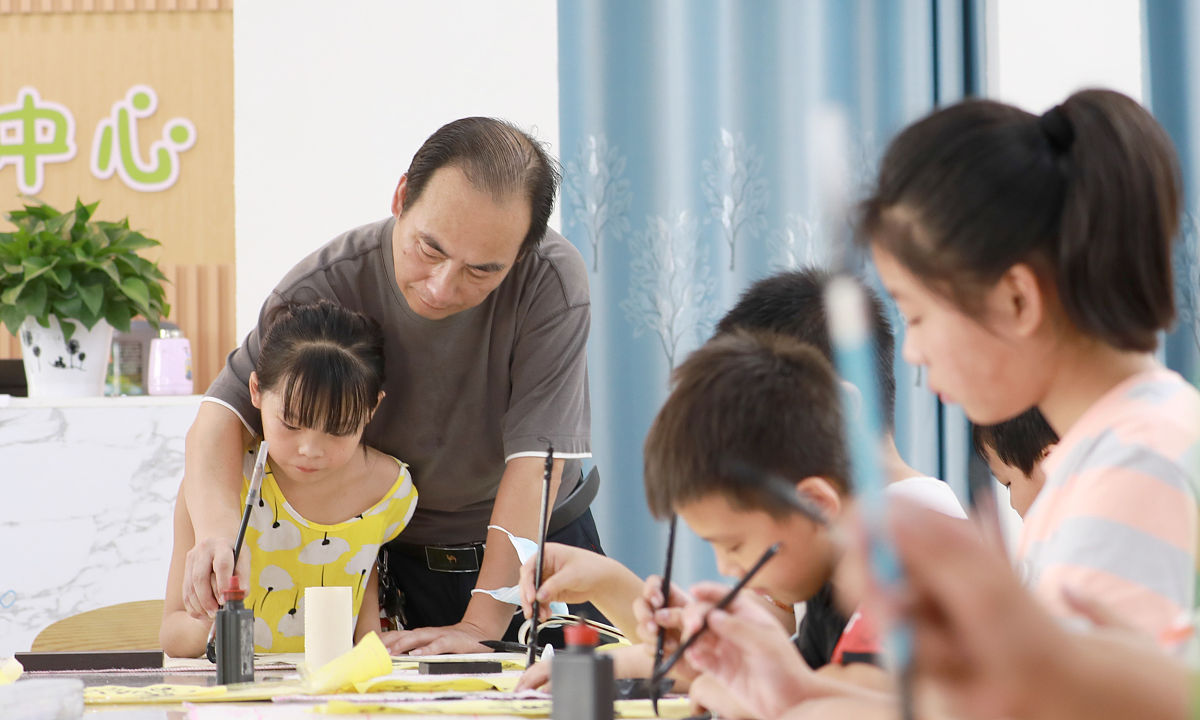 2021年8月3日,四川省华蓥市,一名书法老师在教青少年儿童写毛笔字.