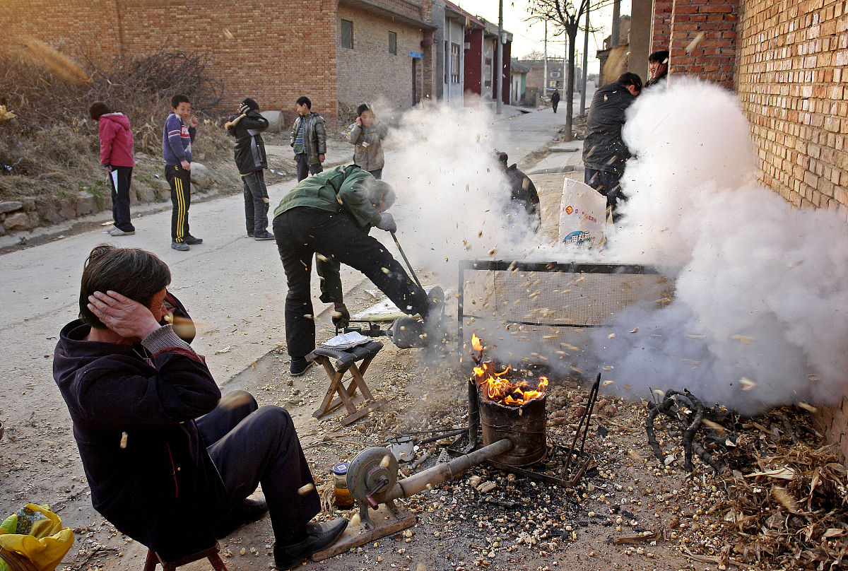 2010年12月11日,山西运城,一位手艺人正在用传统方法为乡亲爆玉米花,
