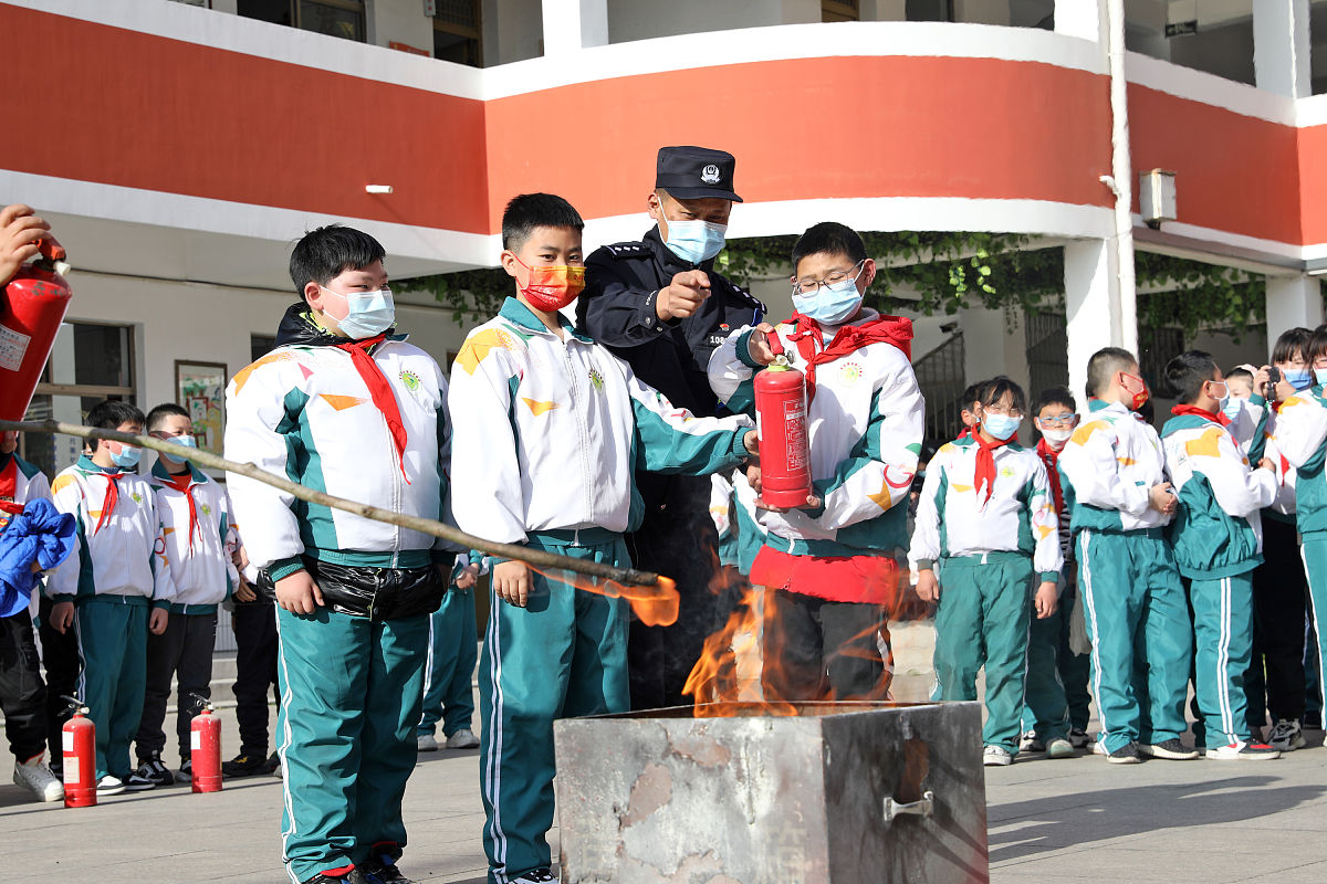 2022年3月28日,在江苏省宝应县泰山小学,民警指导学生们使用灭火器.