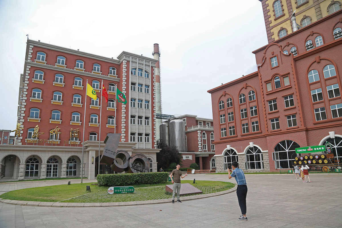 2019年7月9日,游客在青岛啤酒厂厂区外拍照留念.