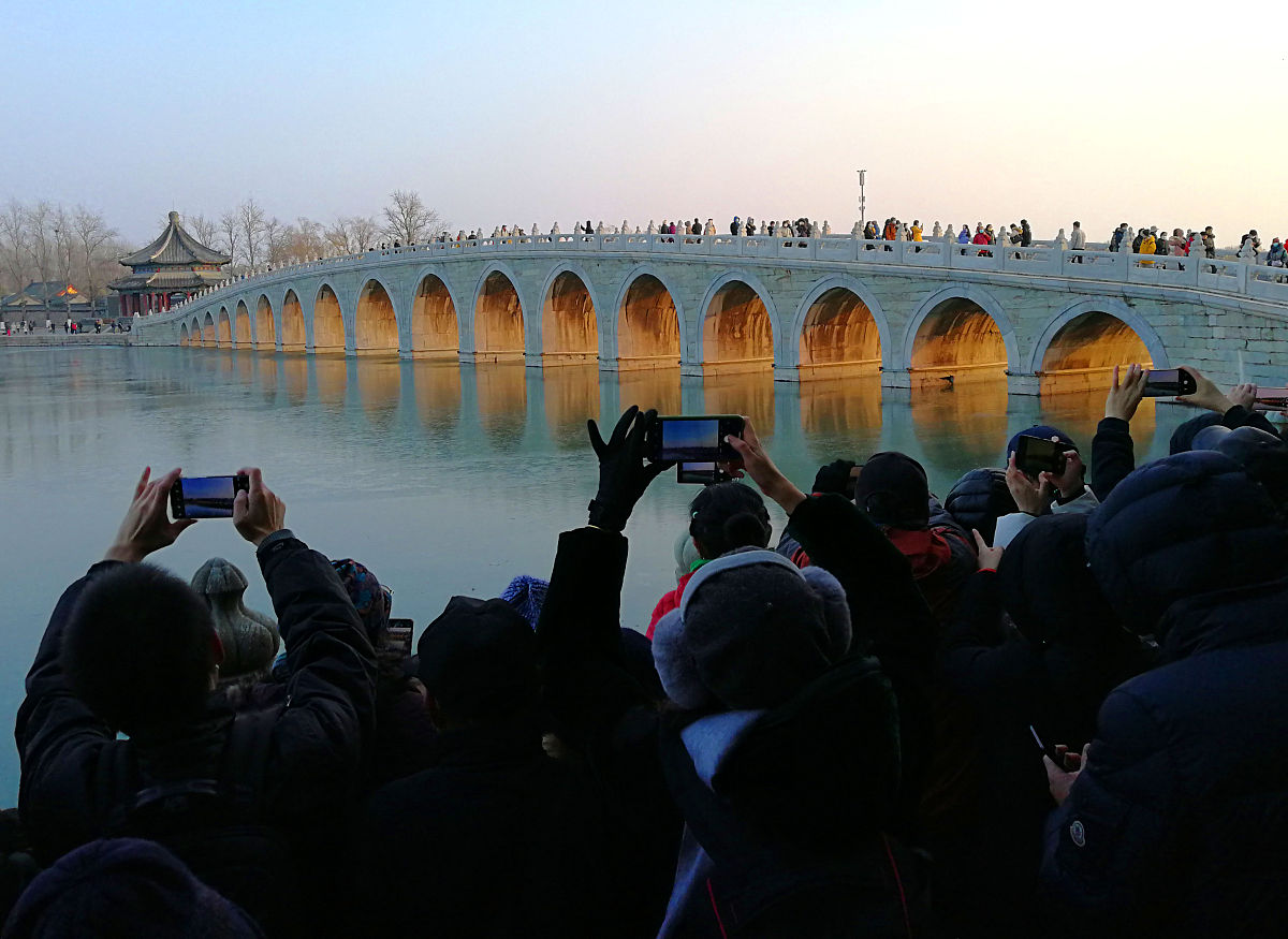 2020年12月6日,北京迎大风降温天气,在颐和园十七孔桥旁,众多游客与摄