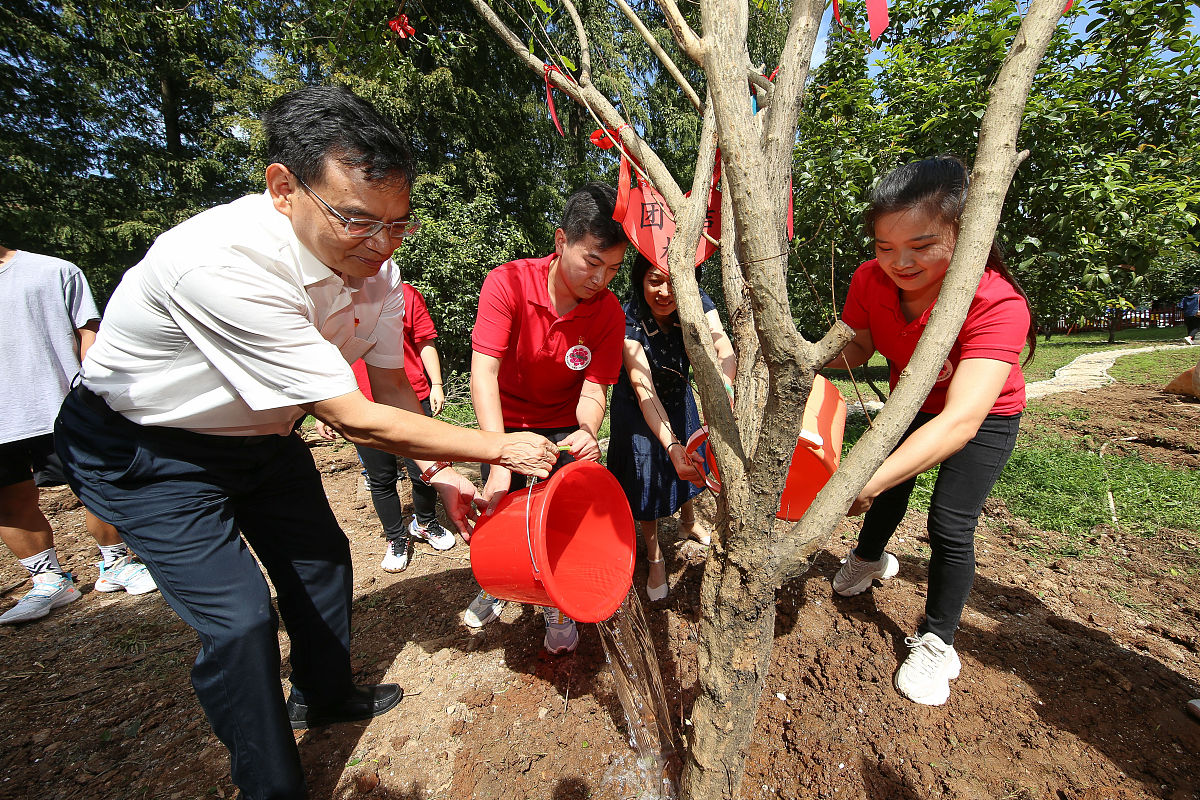 2021年9月9日,湖北省襄阳市,支教队员与学校老师在校内格桑花海种下象
