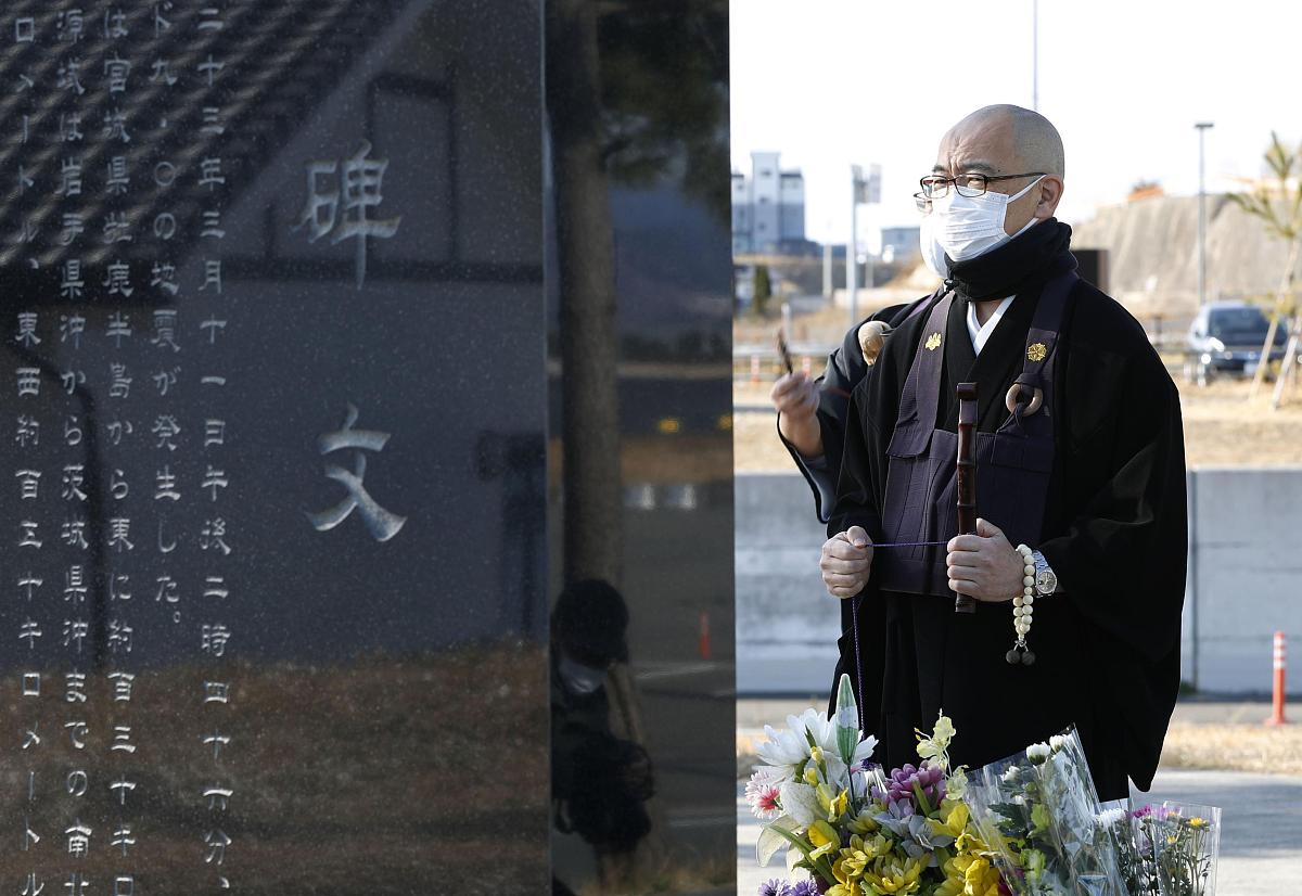 当地时间2021年3月11日,日本相马市,僧侣在纪念碑前祈祷,纪念东日本大