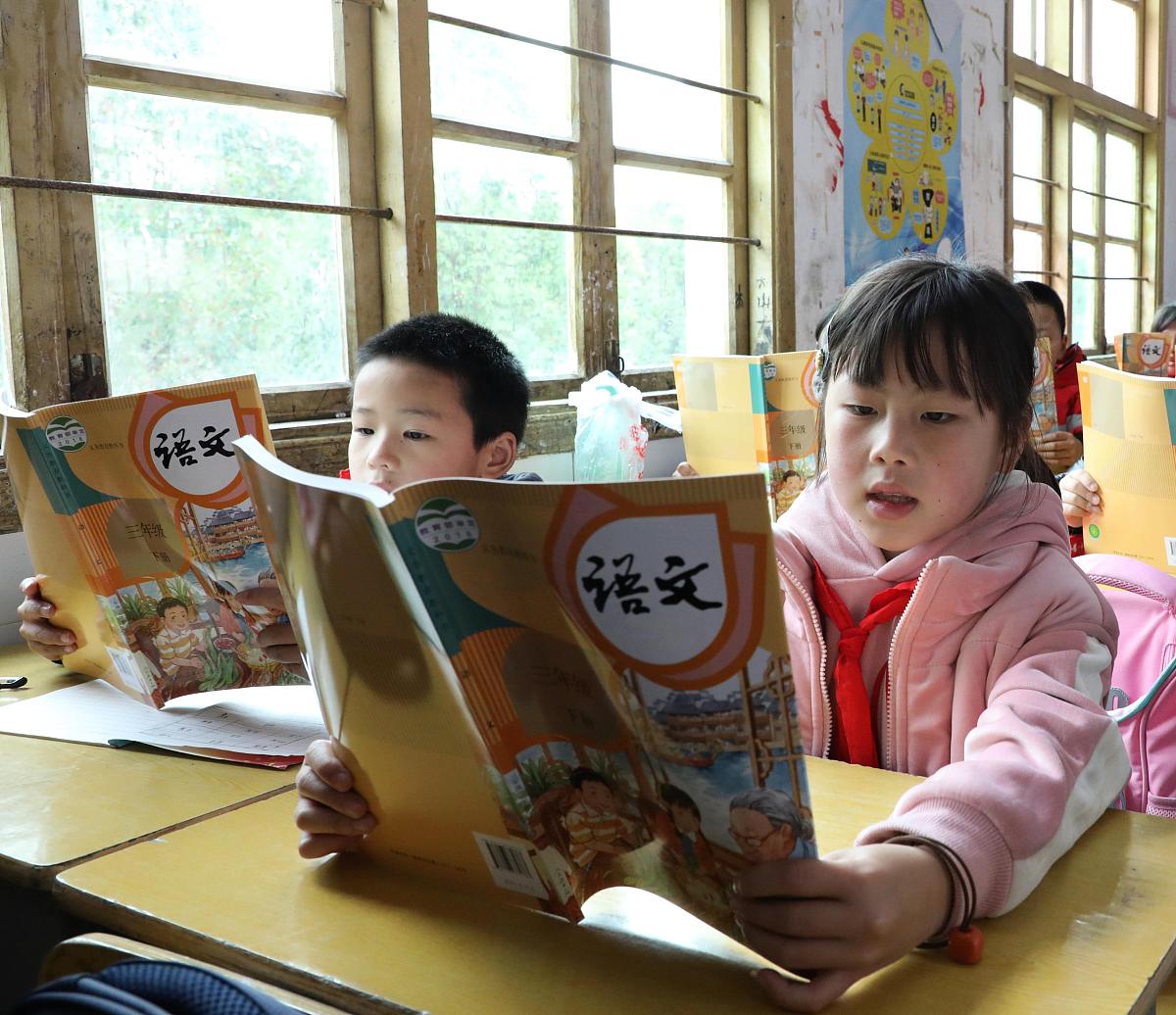 2021年3月8日,湖南省保靖县清水坪学校的留守娃在认真阅读新教科书.