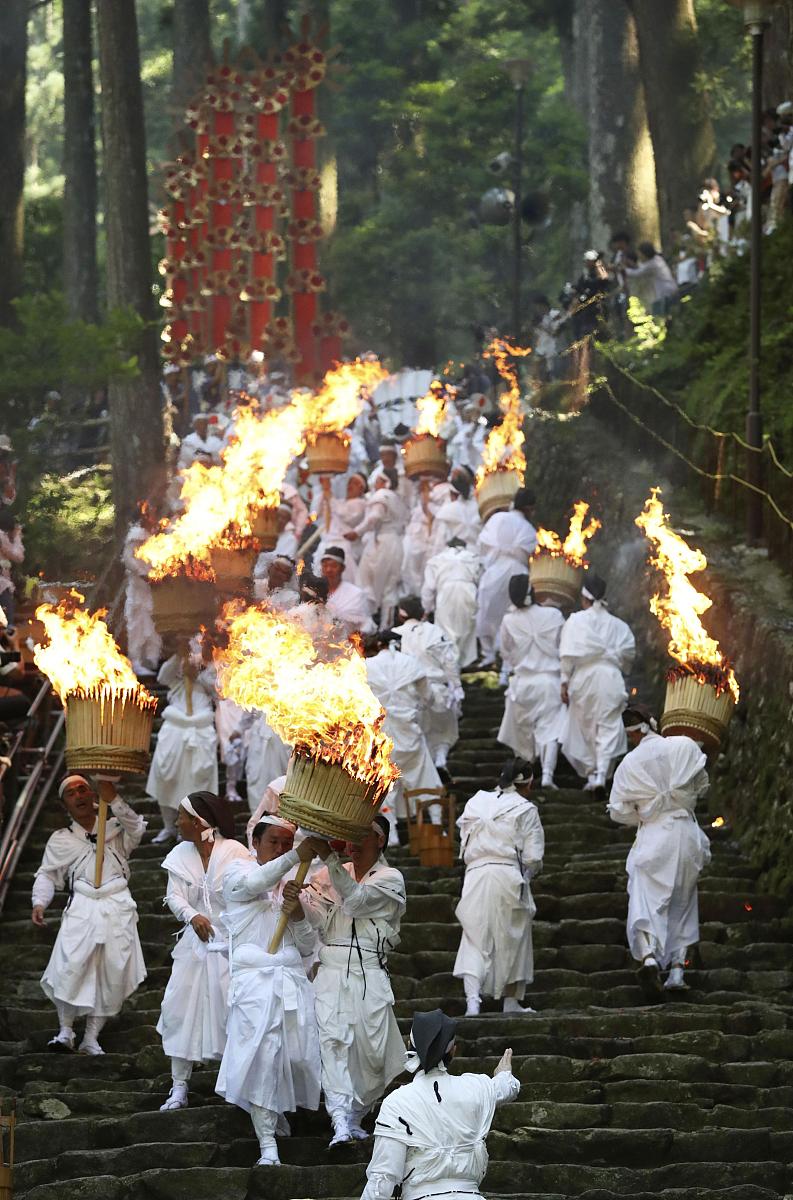 当地时间2018年7月14日,日本和歌山县,穿白袍的男人举着燃烧的火炬,在