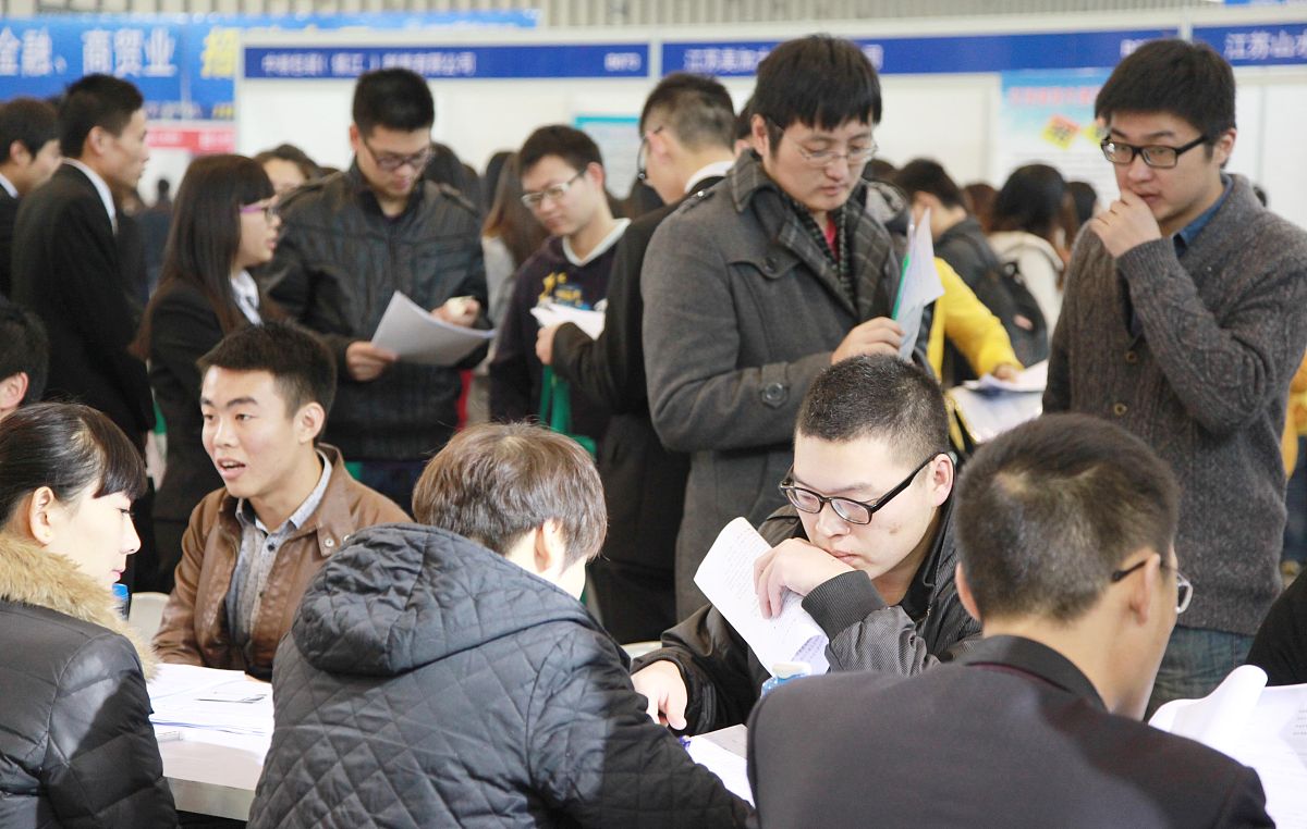 2013年11月20日,江苏省南京市,用人单位代表在与应聘毕业生洽谈.