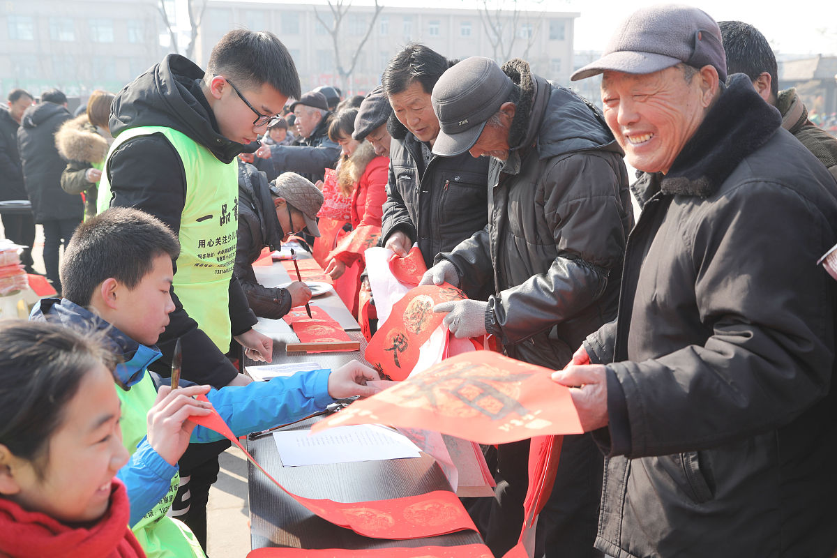 2018年2月7日,江苏徐州,青少年"书法家"为市民书写春联.