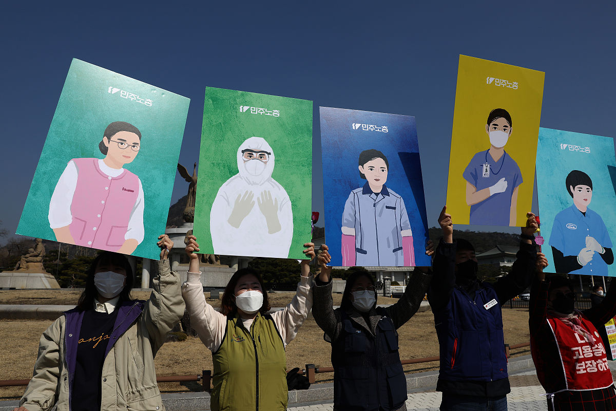 当地时间2021年3月8日,韩国首尔,民众在街头举起牌子与抗议标语,反对