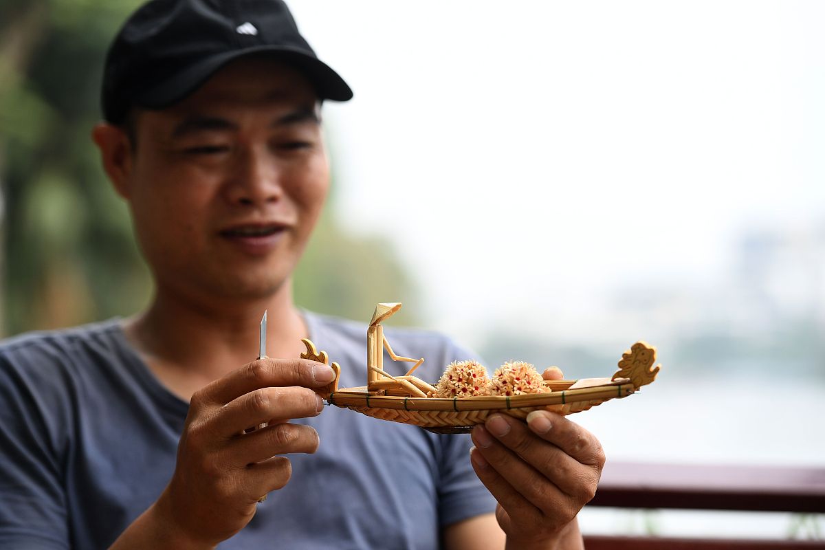 当地时间2020年11月25日,越南河内,一名越南男子展示他制作的微缩竹雕