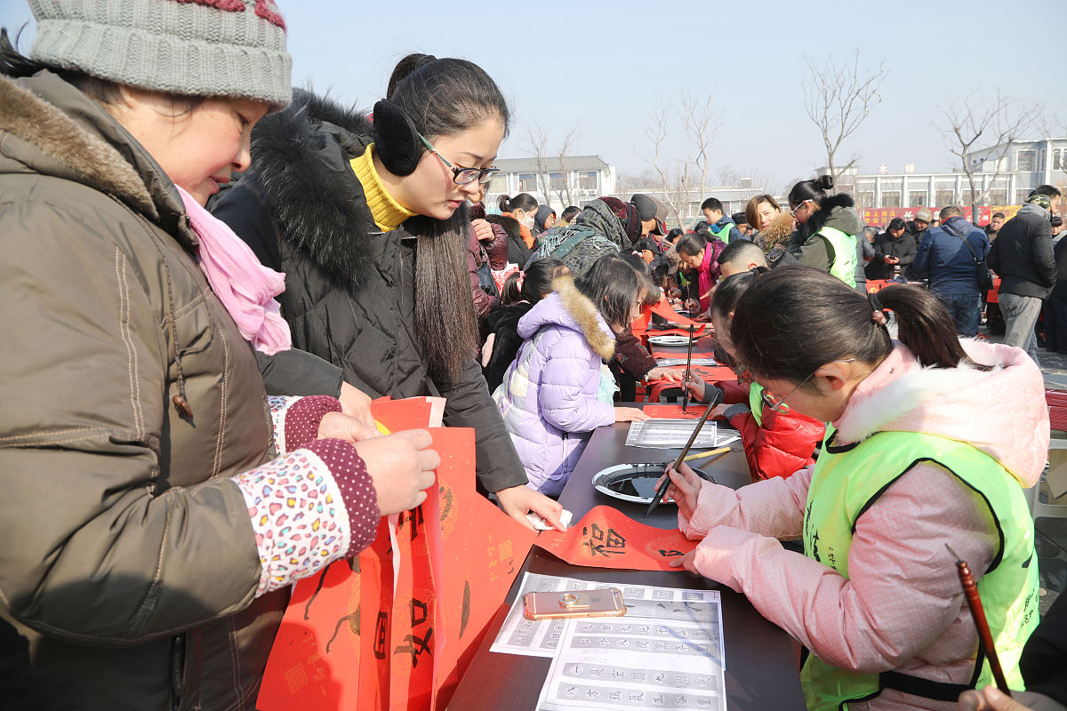 2018年2月7日,江苏徐州,青少年"书法家"为市民书写春联.
