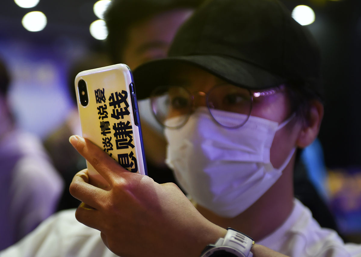 2020年11月18日,举着印有"赚钱谈情说爱"字样手机拍照的年轻人.