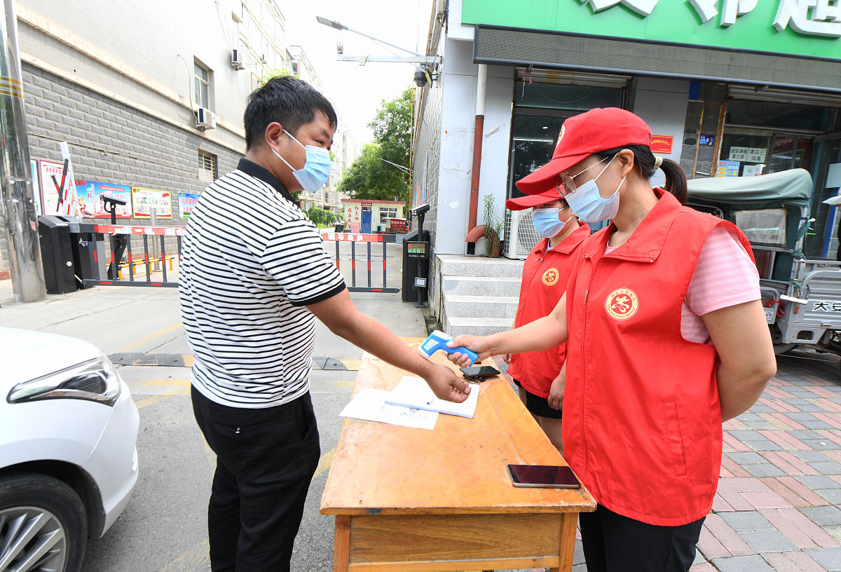 2021年8月12日,在石家庄新乐市一小区门口,两名青年教师志愿者在给外