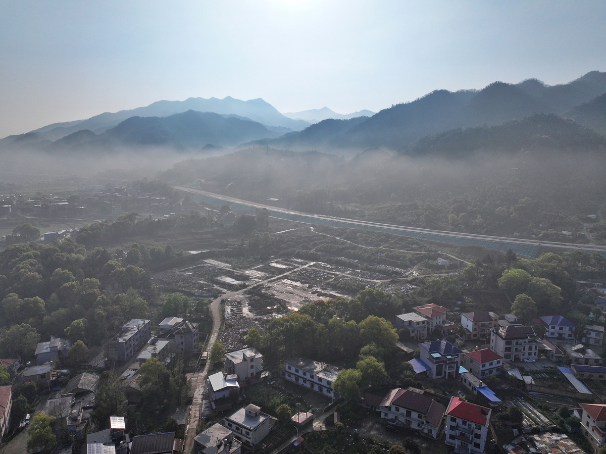 2026年4月1日,江西萍乡,晨雾中的村庄与田园,远处雪山