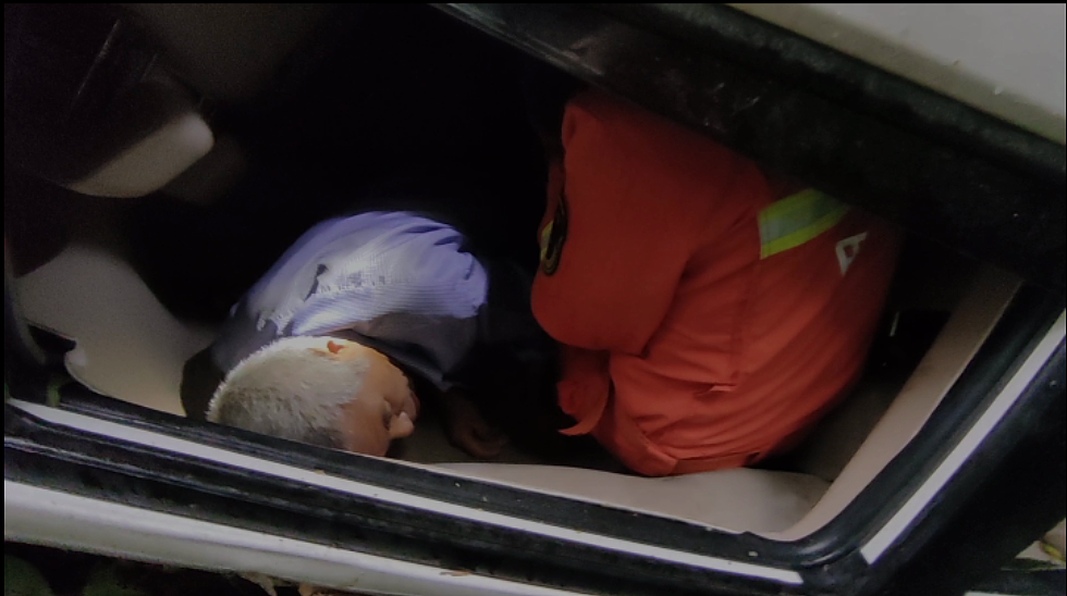 请描写一下一个靠着车门休息的女人抱着一个昏迷的男人然后发现男人突然醒了的画面