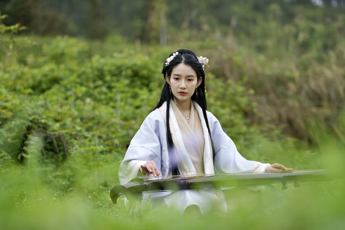 通过以下描述写一首古诗：一轮满月洒下金色的月光照在树枝上出现斑驳的影子树下一位身穿汉服的妙龄少女轻抚古筝奏起悠扬的音乐。