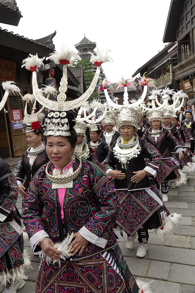 2020年4月25日,贵州黔东南,苗族妇女身着节日盛装在万达小镇街道上载