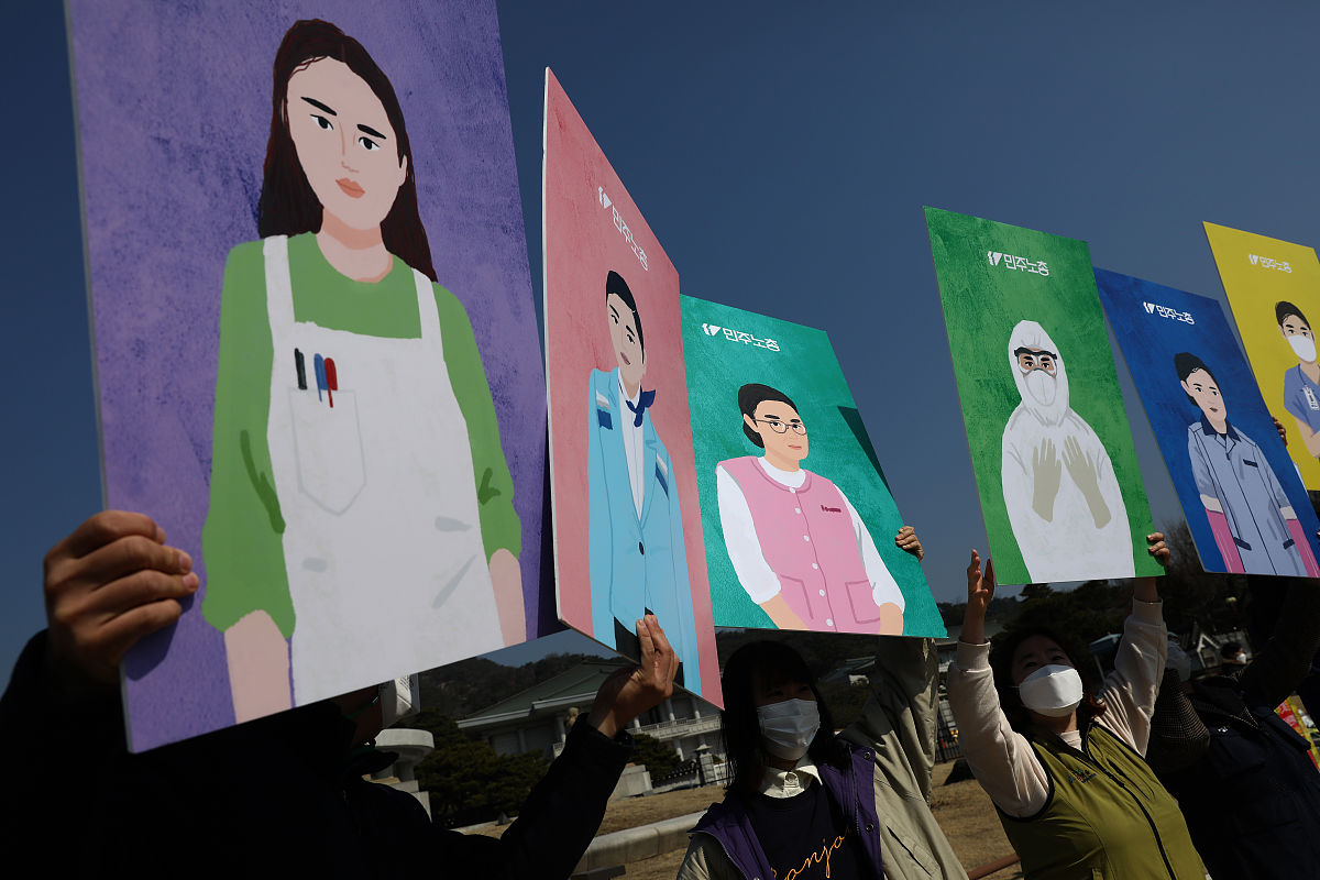 当地时间2021年3月8日,韩国首尔,民众在街头举起牌子与抗议标语,反对