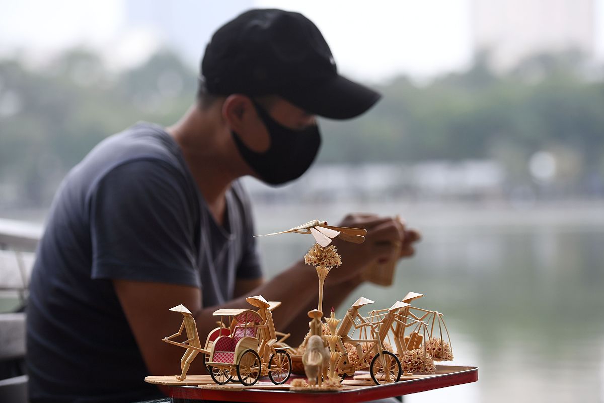 当地时间2020年11月25日,越南河内,一名越南男子展示他制作的微缩竹雕