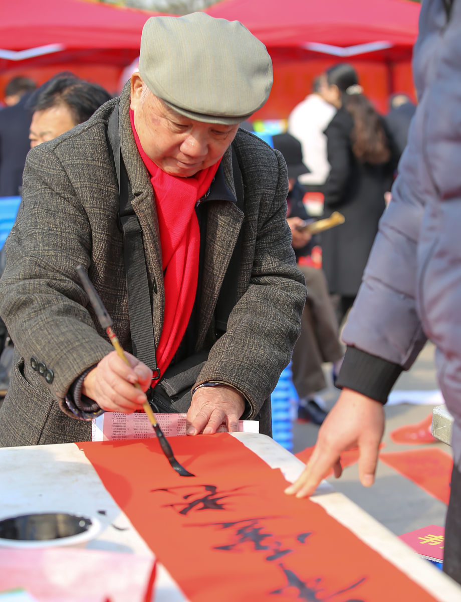 2018年2月3日,广西柳州,书法家梁庆逢为市民书写春联.
