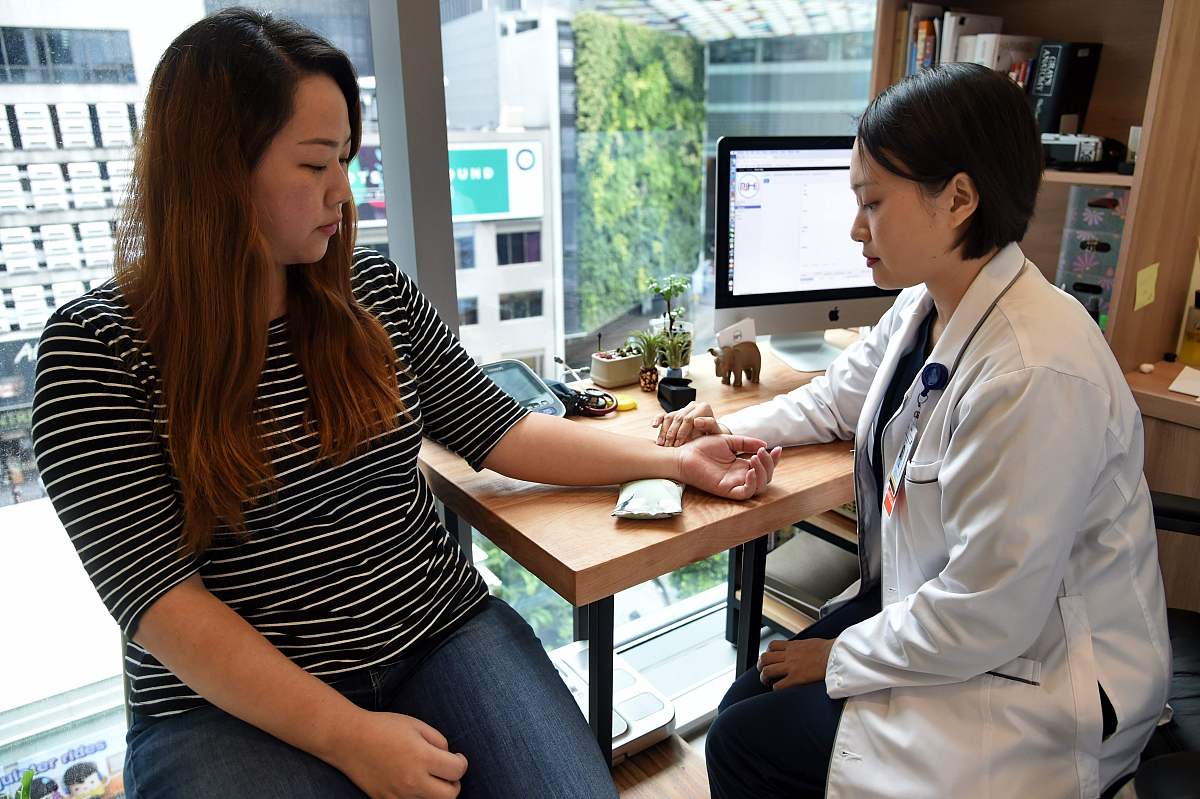 当地时间2017年10月12日,新加坡,novahealth诊所的医生为患者把脉.为