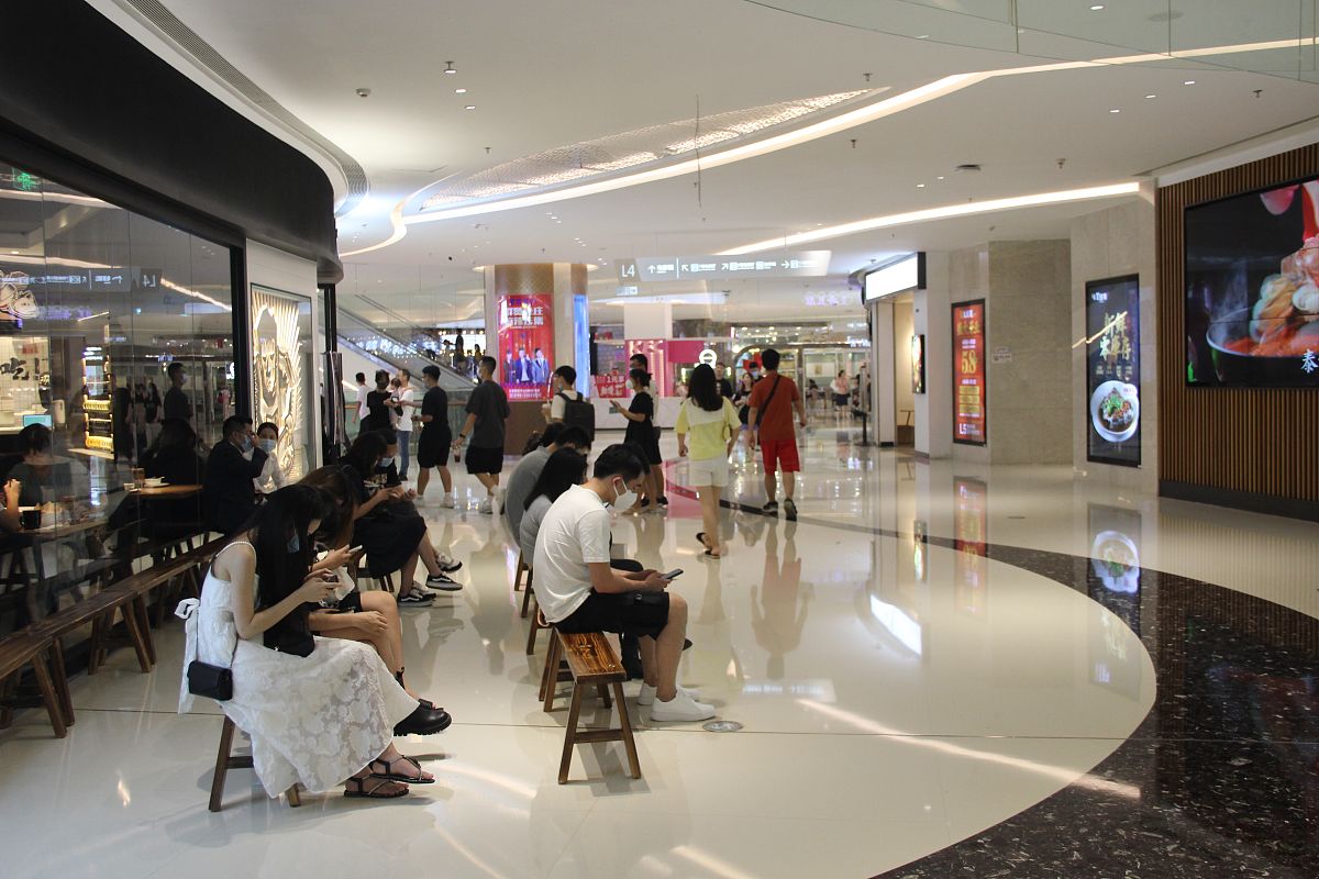 2021年6月6日,广东省东莞市,民盈国贸城,人们一边玩手机一边等叫号进