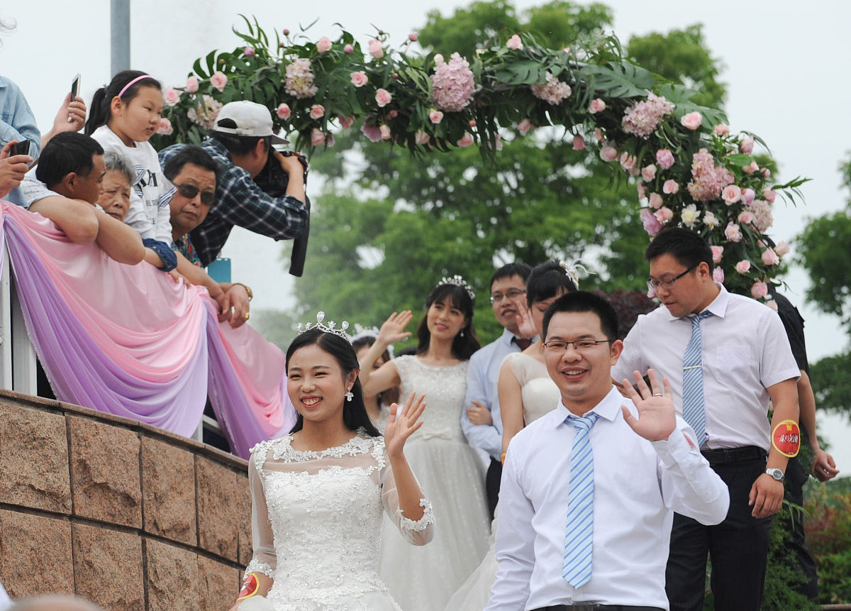 湖北武汉市青山江滩婚姻登记处将举办情定七夕公益集体婚礼活动有20对新人报名参加现场将 派发牵巾新人入场领导致辞沃盥礼却扇礼宣读誓言新人按下诺印拜天地合卺礼颁证仪式锁同心锁参观婚俗文化长廊等流程。现场将拍摄新闻写一个新闻标题。