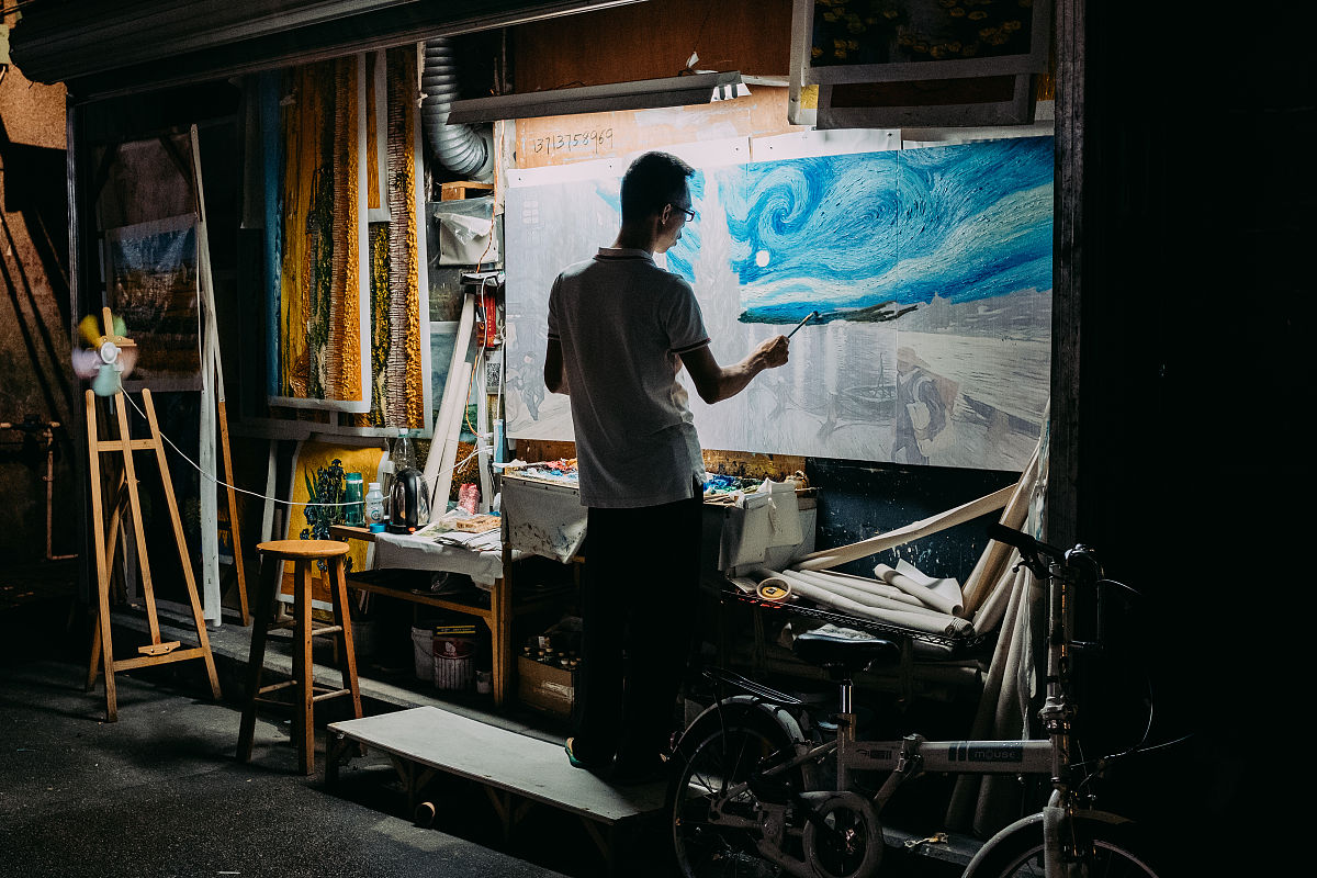 2018年7月20日,深圳,大芬油画村的晚上,画师正复制梵高的作品,油画村