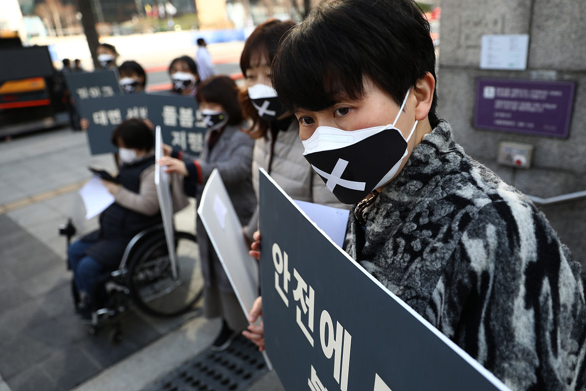 当地时间2021年3月8日,韩国首尔,民众在街头举起牌子与抗议标语,反对