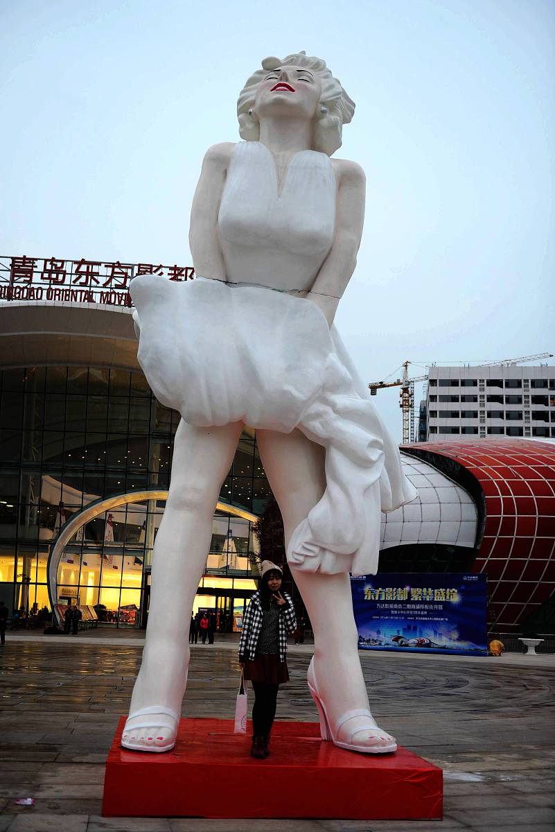 2014年11月15日,山东青岛,一位游客在与巨型梦露塑像合影.