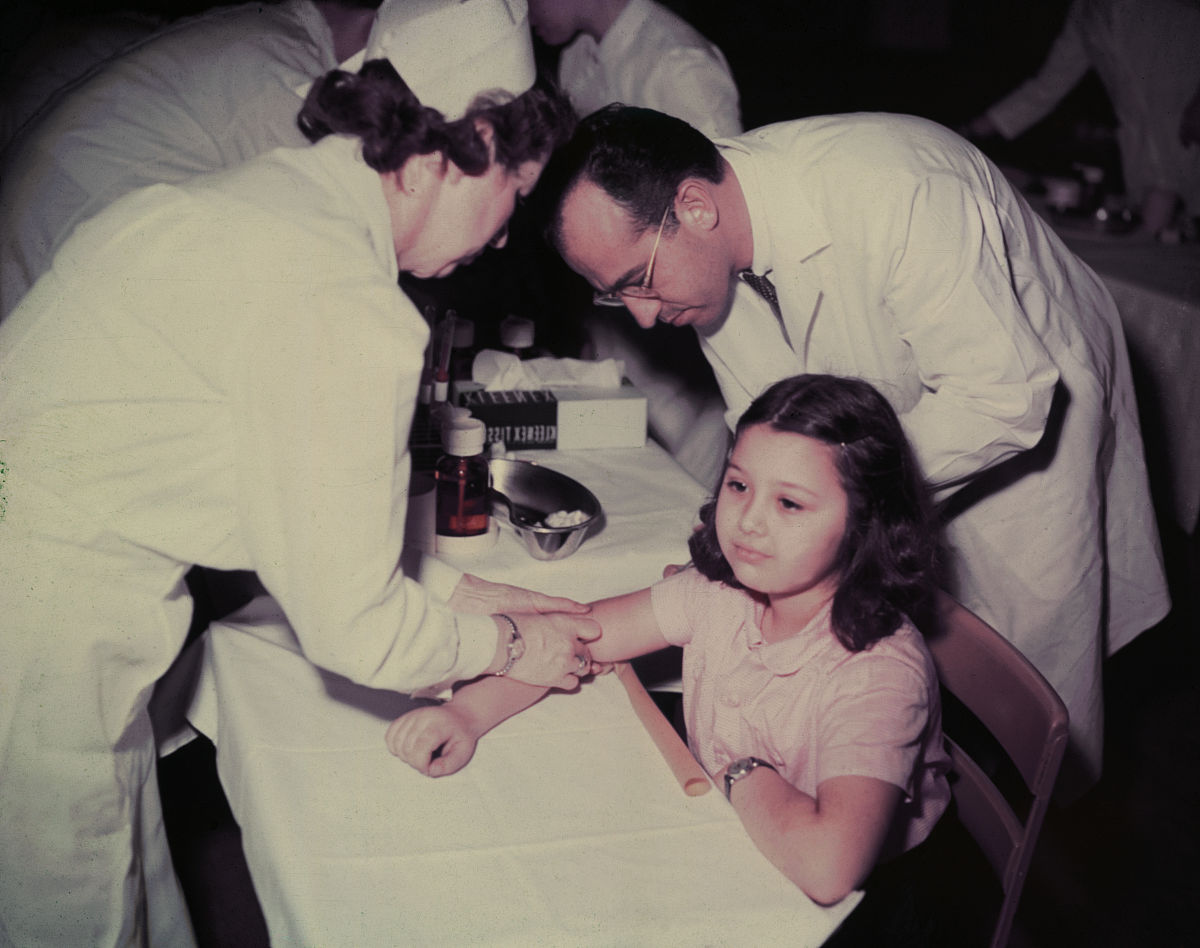 1950年代,美国匹兹堡市,乔纳斯·索尔克博士与护士为一名小女孩paulin