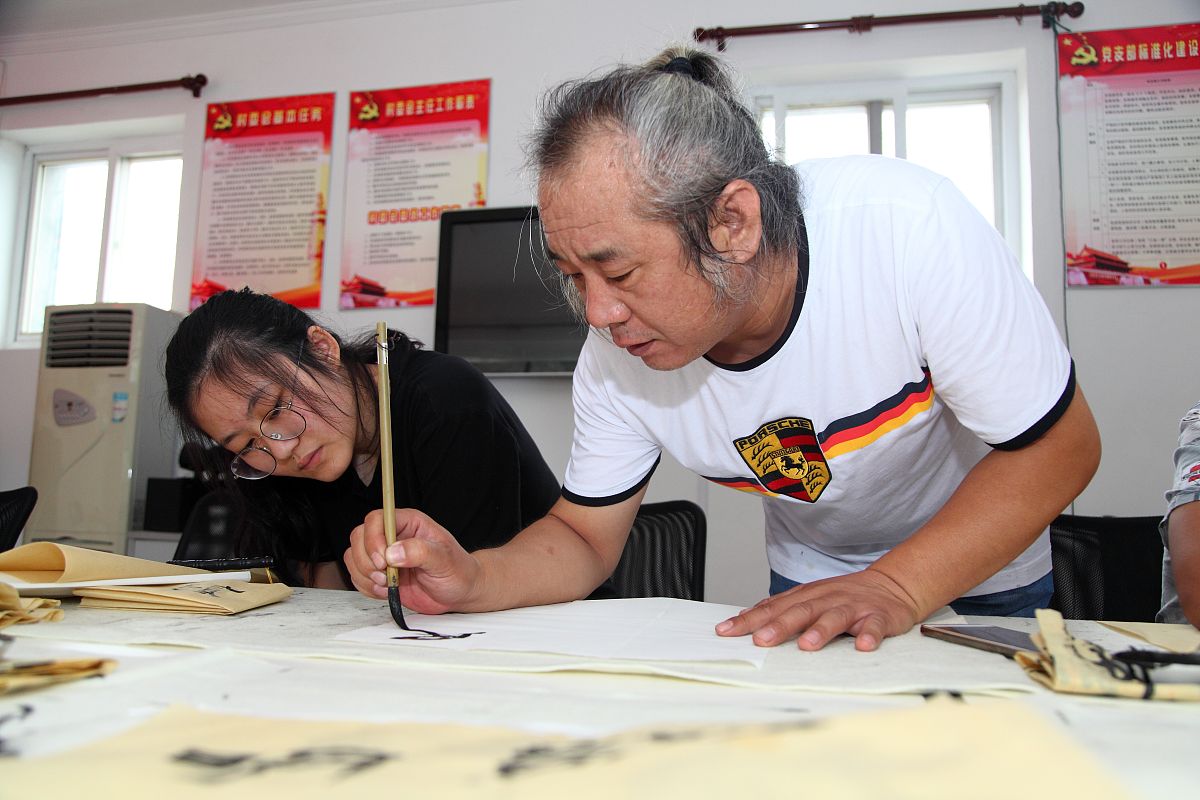 2018年7月27日,北京,书法教师在耐心指导学员.