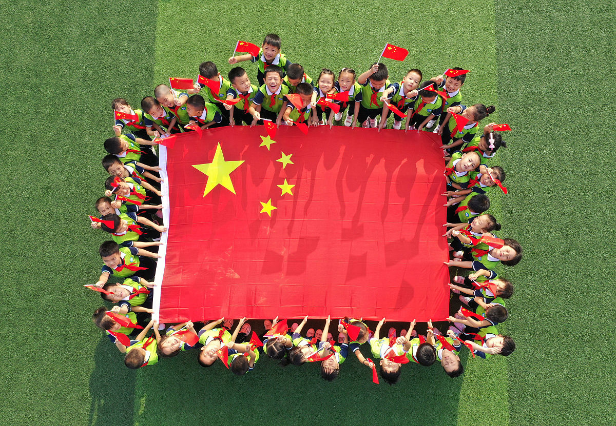 2019年9月19日,湖南永州,道县第一小学的学生与国旗合影.