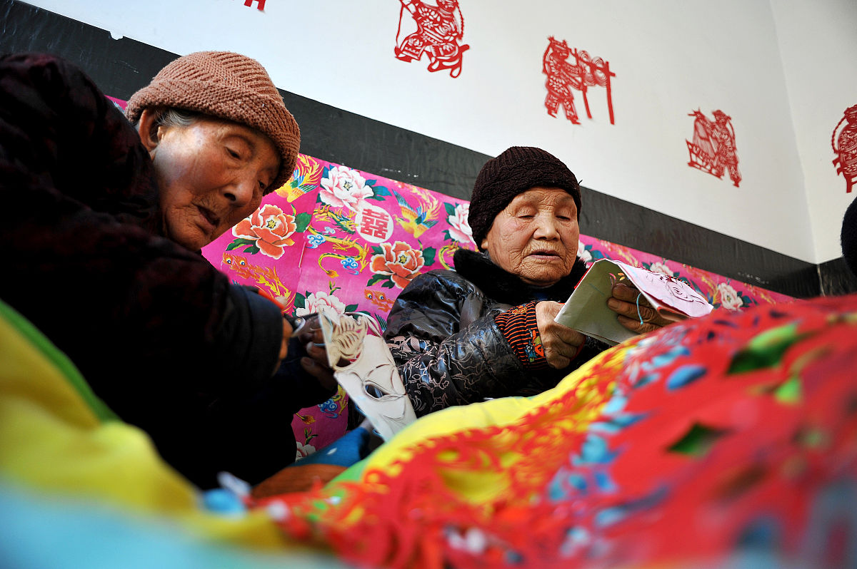 2014年12月21日,山西永济,86岁的李三女(右)和88岁的李玉梅正在剪纸.