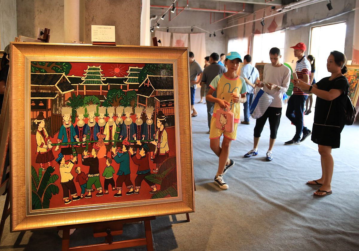 2017年10月1日,在广西柳州市窑埠古镇,游人在观看三江侗族农民漆画展.