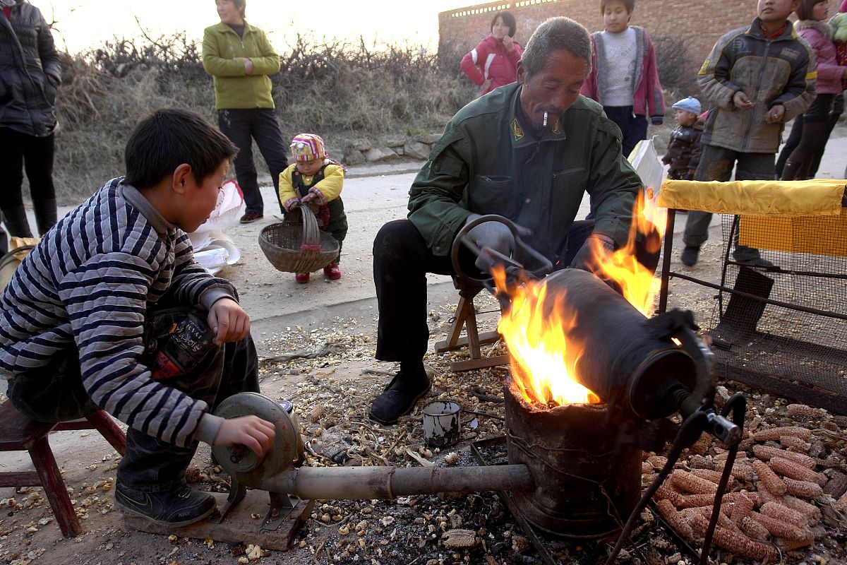 2010年12月11日,山西运城,一位手艺人正在用传统方法为乡亲爆玉米花,