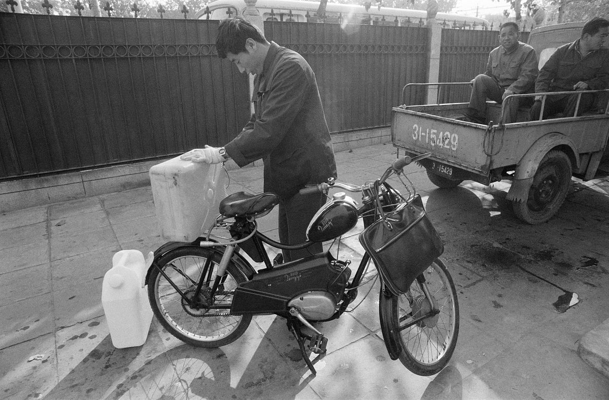 1980年10月,北京,一个男人正在街头移动的灌装式加油站给自己的车加油